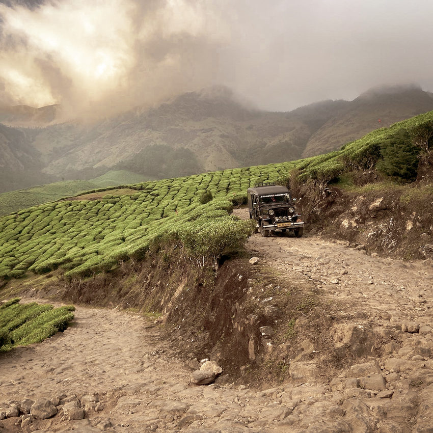 Green hills and a rough road through the landscape of Munnar.