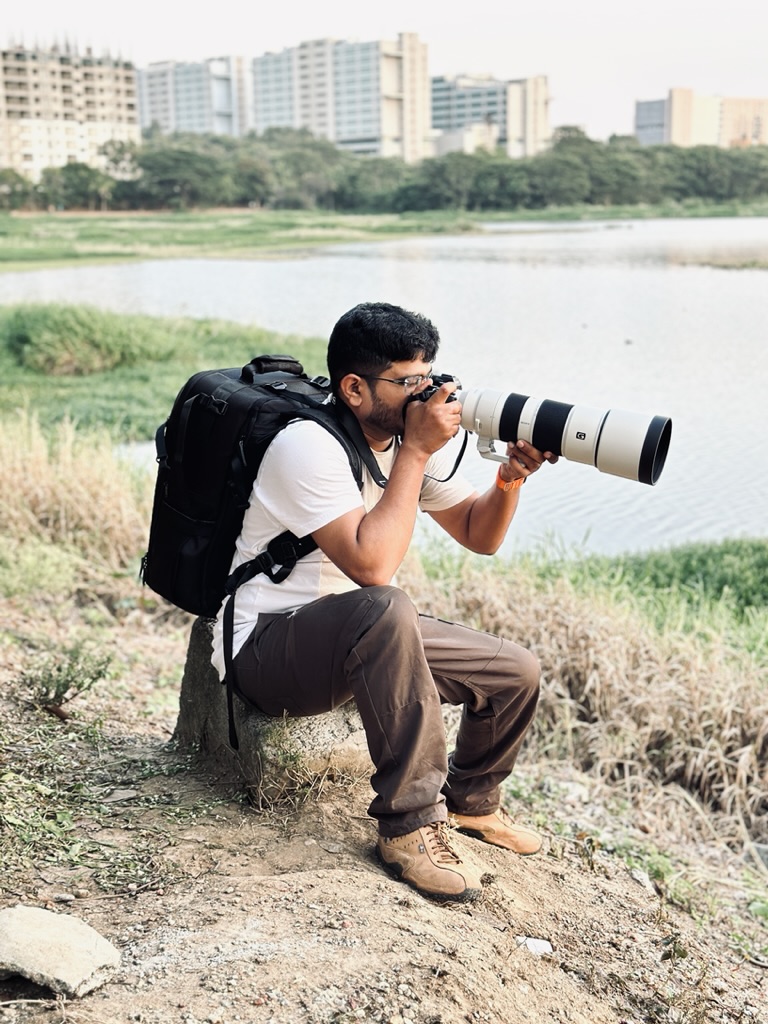Sandeep photographing beside a lake with a long telephoto lens.